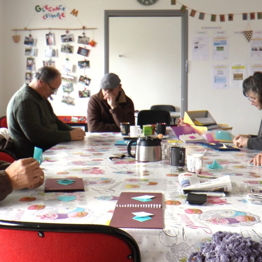 Plusieurs adultes du Groupe d'entraide mutuelle s'exerce au pliage