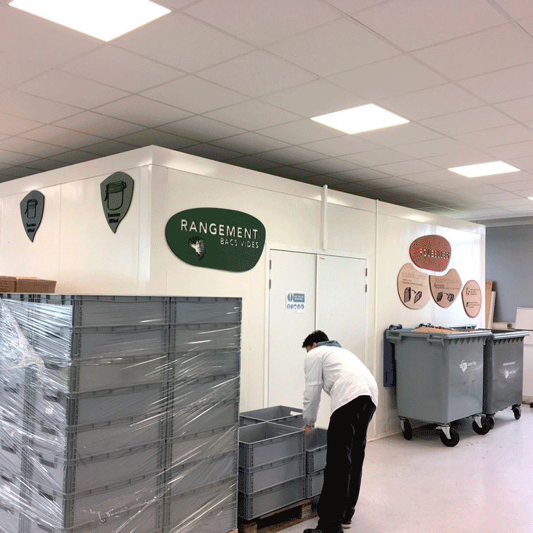 EMERAUDE ID signalétique vue d'ensemble de l'atelier. On y voit les conteneurs,, les bacs de rangement et la signalétique coloré marquant les espaces. Mot clé : design-inclusif signalétique-accessible design-d'espace