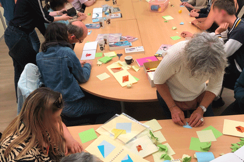 Classe ulis tout le groupe réuni pour plier et replier , les lycéens de la classe ULIS, les salariées de l'ESAT et les personnes du Satra. grande tablée avec plein d'origami et de personnes qui travaillent ensemble