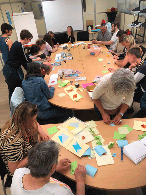 Classe ulis tout le groupe réuni pour plier et replier , les lycéens de la classe ULIS, les salariées de l'ESAT et les personnes du Satra. grande tablée avec plein d'origami et de personnes qui travaillent ensemble