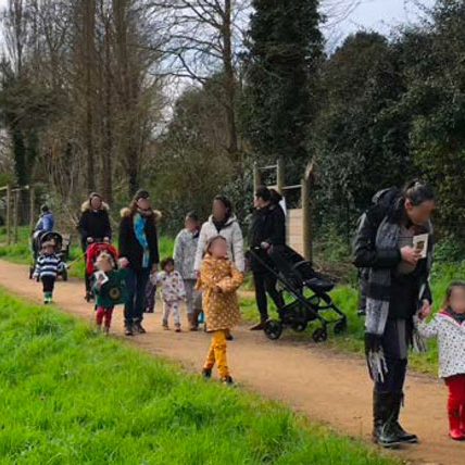 CHASSE A L OURS lecture et randonnée sensorielle la photo montre le groupe sur le sentier entre deux étapes, les enfants tiennent dans leur main un petit cercle qui leur permet de savoir vers quel environnement naturel il faut se diriger.